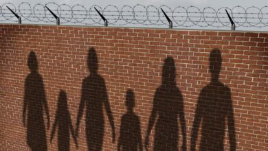 Family silhouettes on brick wall topped with barbed wire