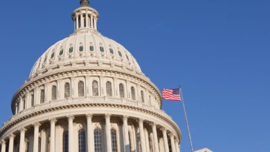 Close view of Capitol dome and American flag against blue sky