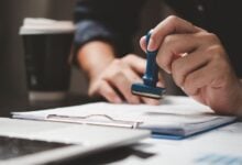 Person stamping immigration documents on a desk